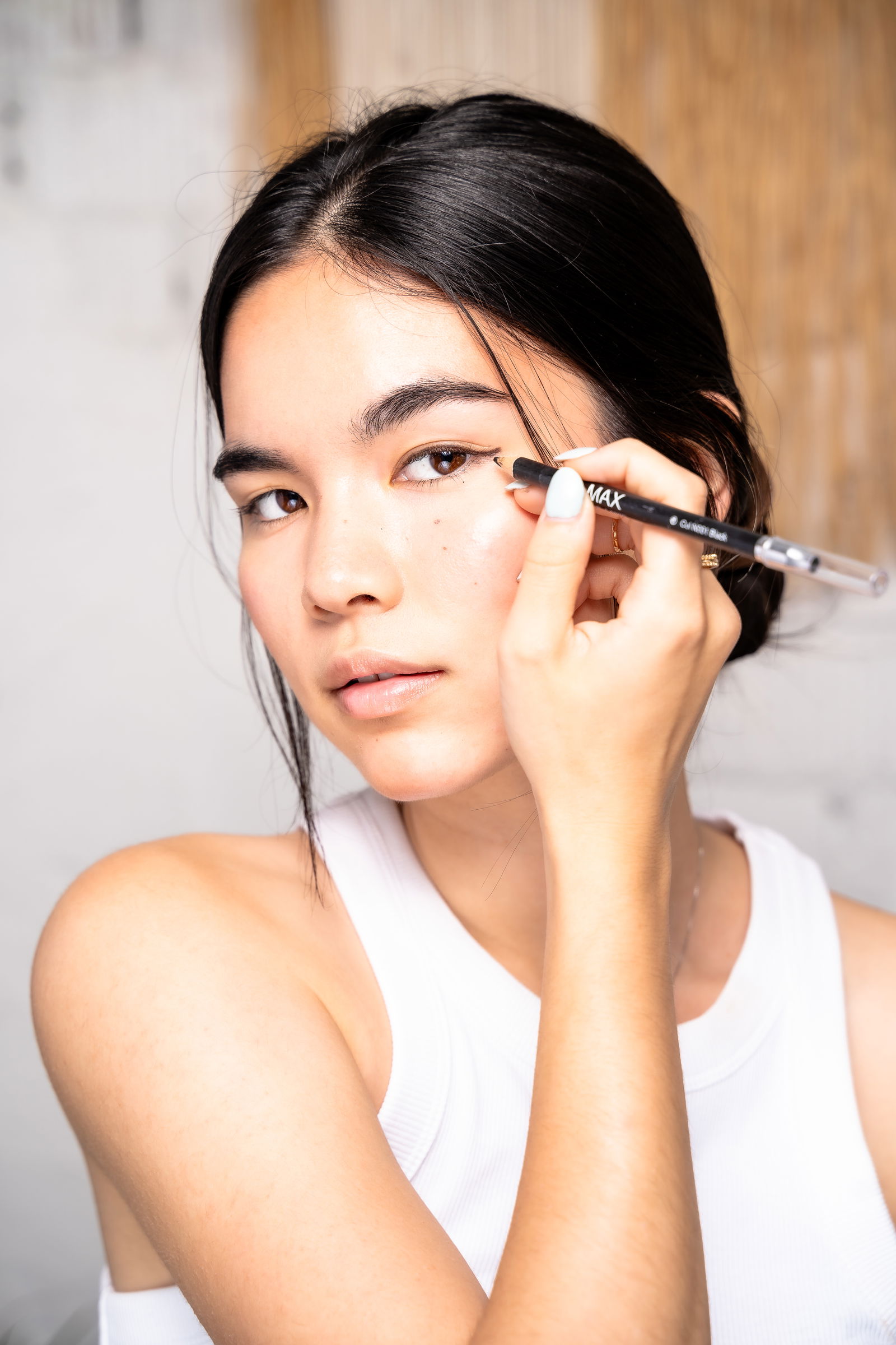 Woman drawing pencil eyeliner on in tutorial on applying winged eyeliner