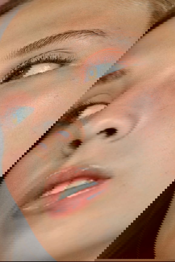 Close-up of a young woman's face with green eyes, soft make-up and beautiful skin looking to the side