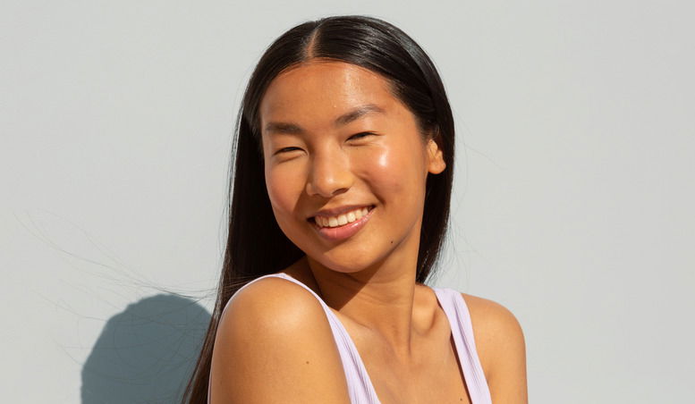 Happy woman with great positive energy. She is wearing a white bra and is enjoying the summer's sun. She is smiling and the portrait is shot against an isolated background. shiny shiniest hair