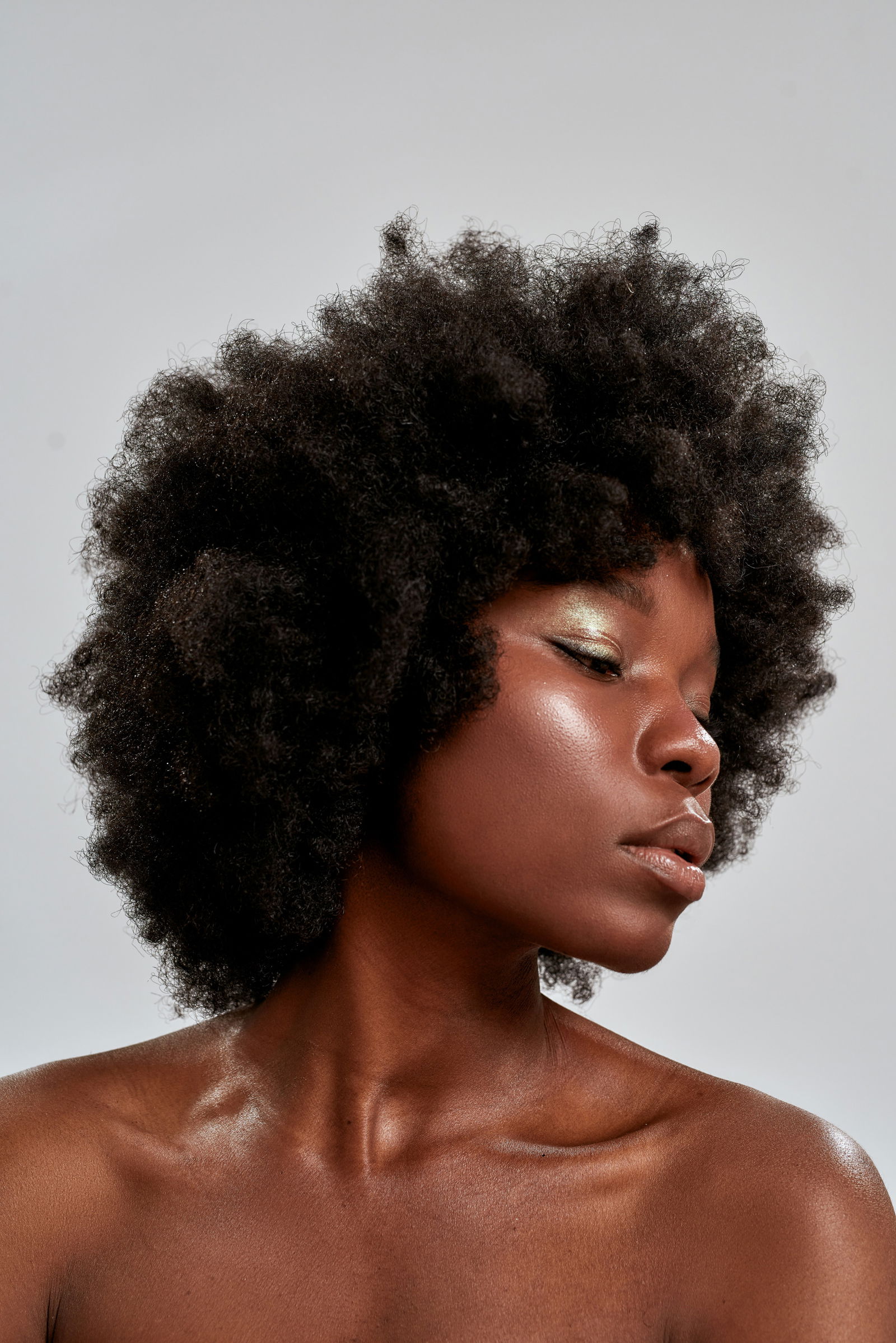 botox injections woman skin Portrait of beautiful african american female model with afro hair and perfect smooth glowing skin looking down posing isolated over gray background