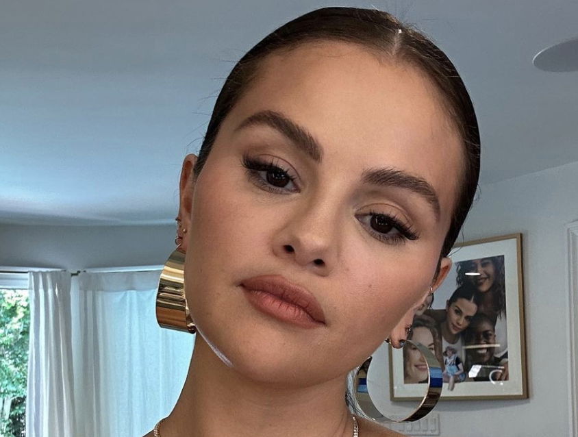 Selena Gomez with winged eyeliner and a middle parting bun