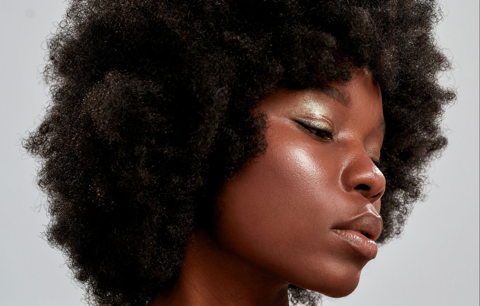 Woman with a dark skin tone showing how to pick the perfect blusher hair