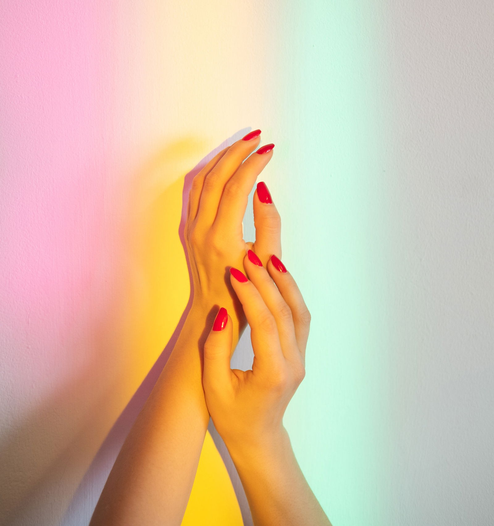 Smooth skin care. Treatment protection. Moisturizing nutrition. Neil beauty salon. Female hands with red polish tenderly holding together on wall blur rainbow overlay glowing lights. how to remove acrylic nails at home