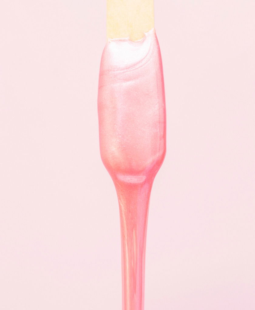 liquid wax for pink depilation drains from the stick. The concept of depilation, waxing, smooth skin without hair. brazilian wax