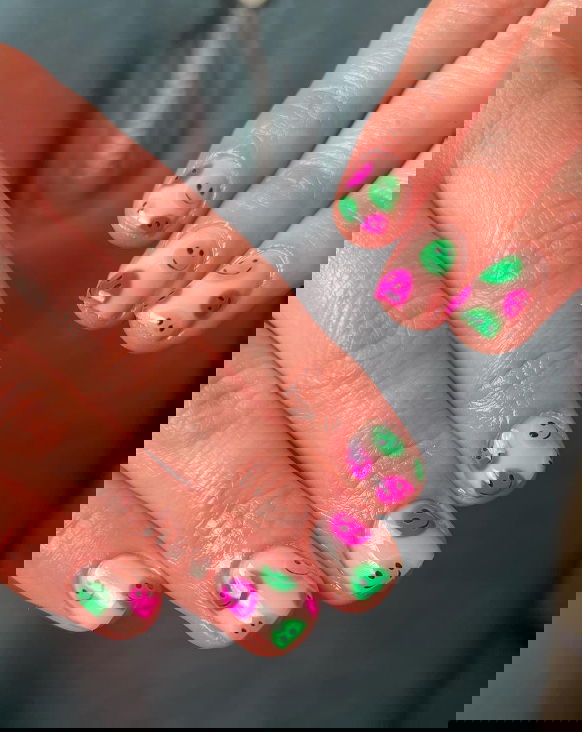 pink and green smiley face nail design