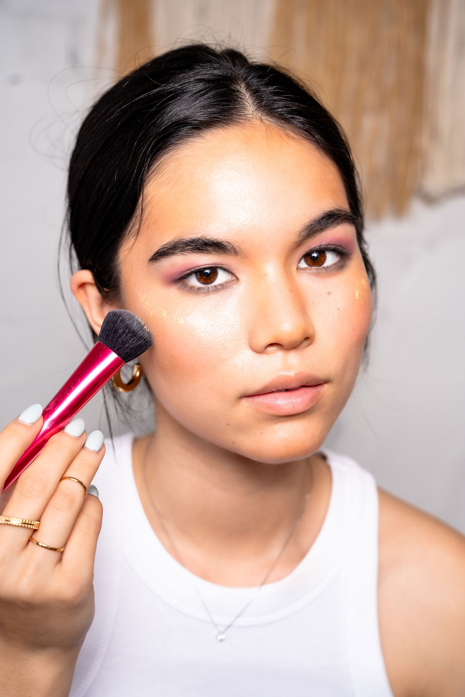 Girl showing how to apply highlighter to your cheekbones