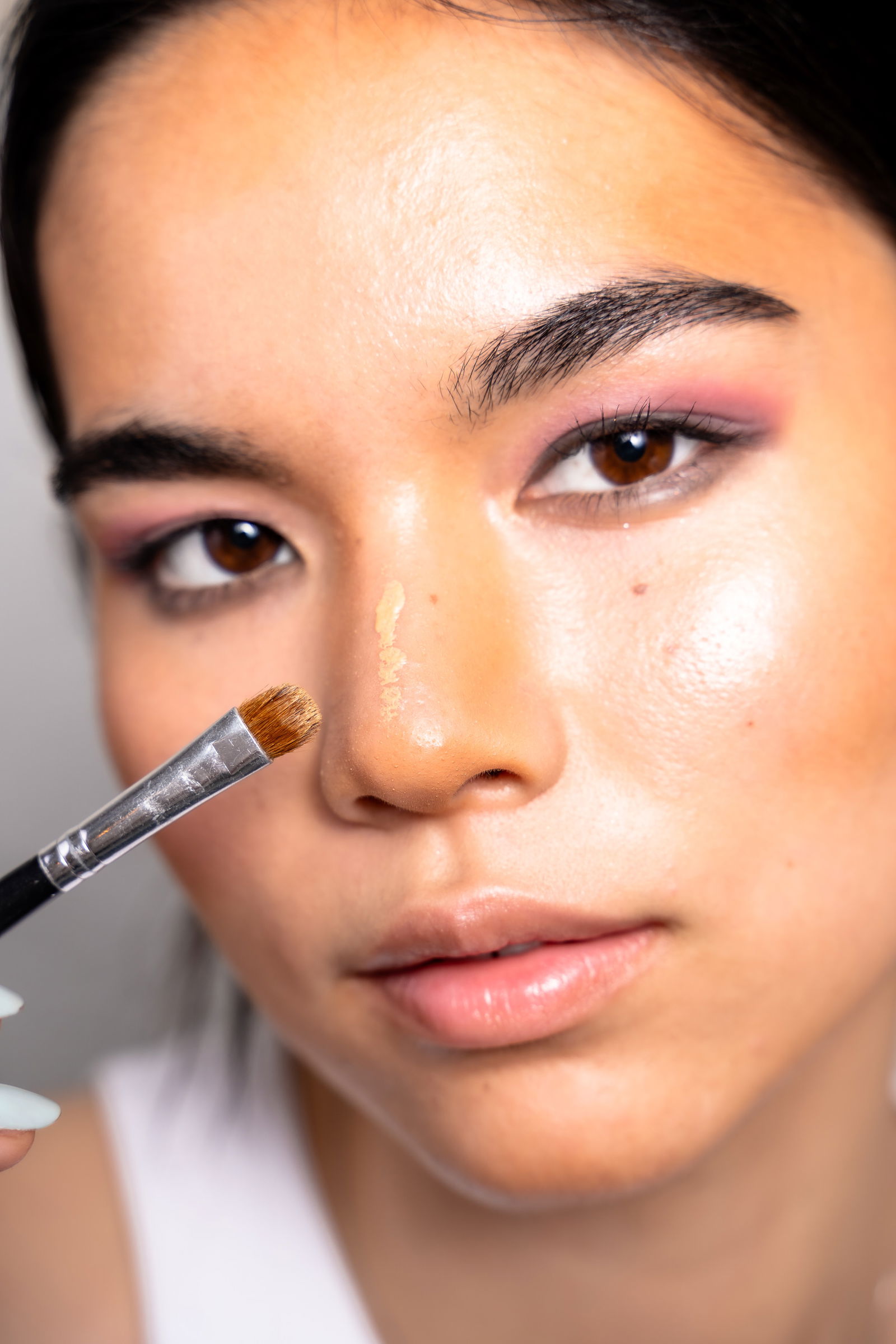 Girl showing how to apply highlighter to the bridge of your nose