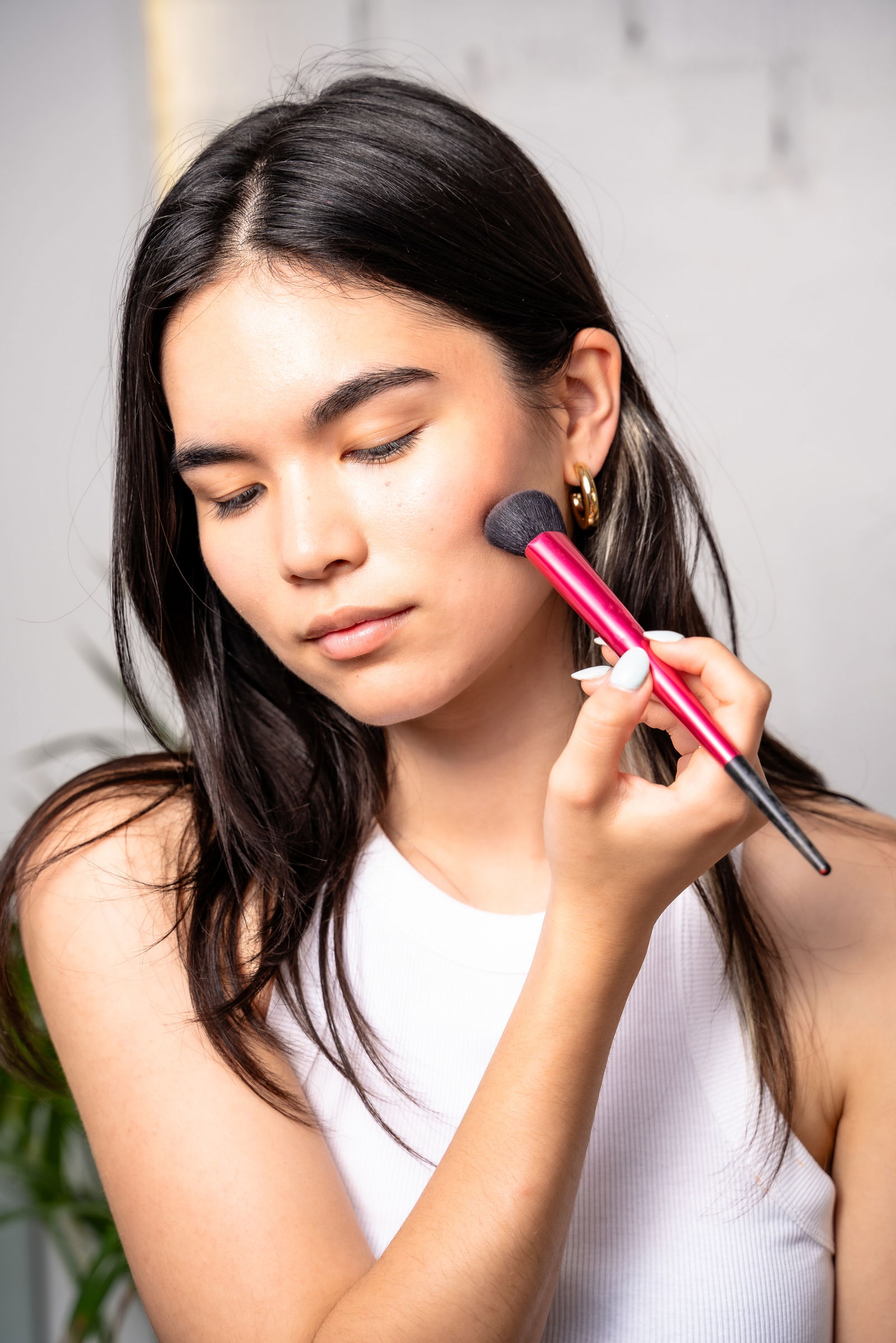 Girl applying bronzer to cheekbones