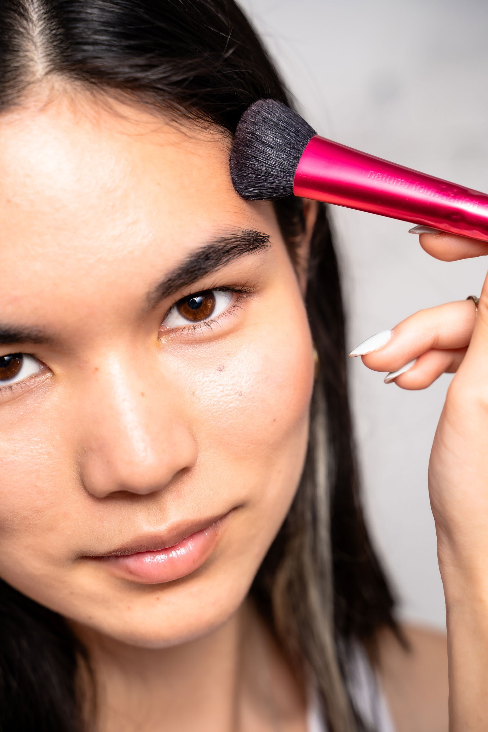 Girl showing how to apply bronzer to her forehead