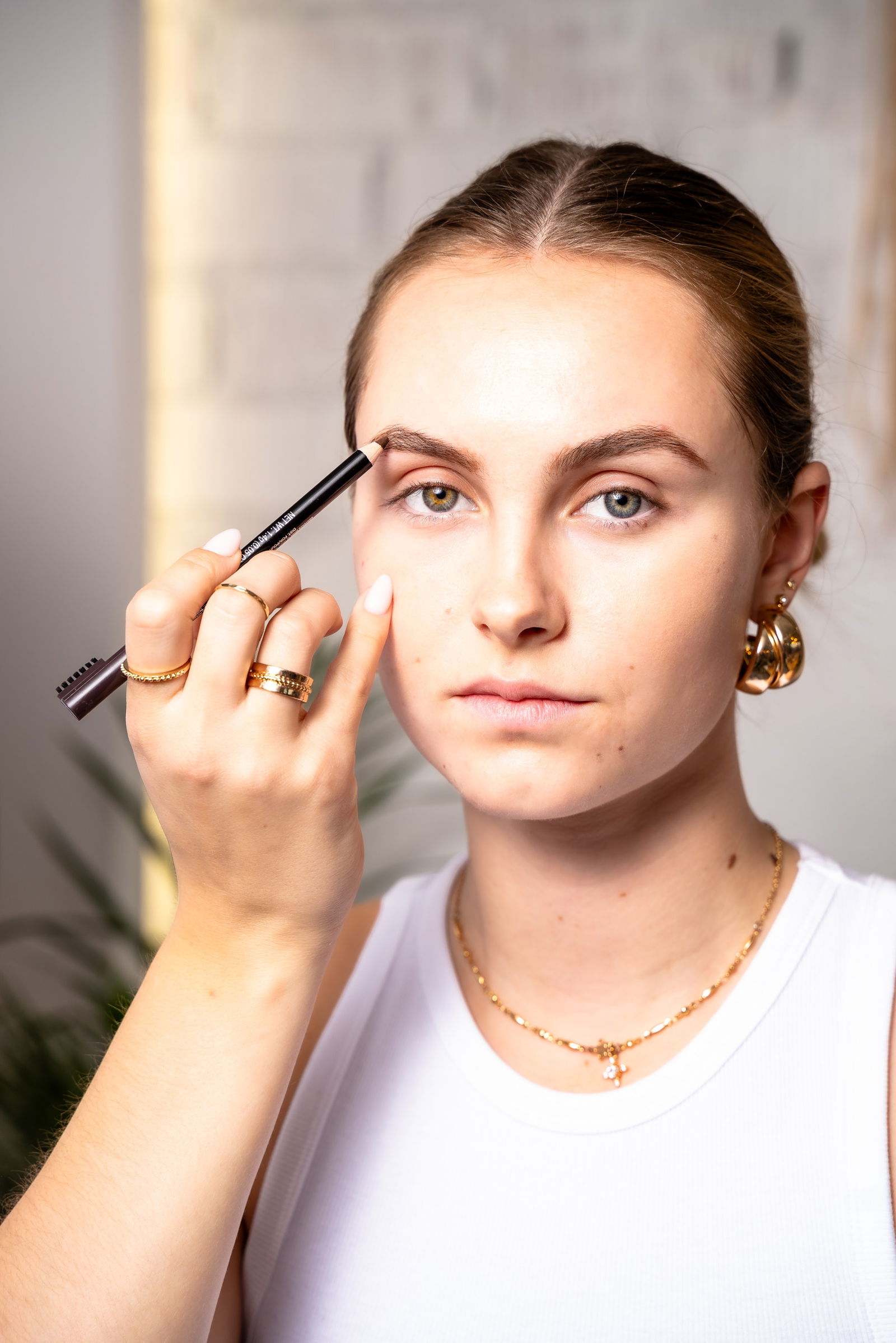 Girl showing how to use an eyebrow pencil to do her brows