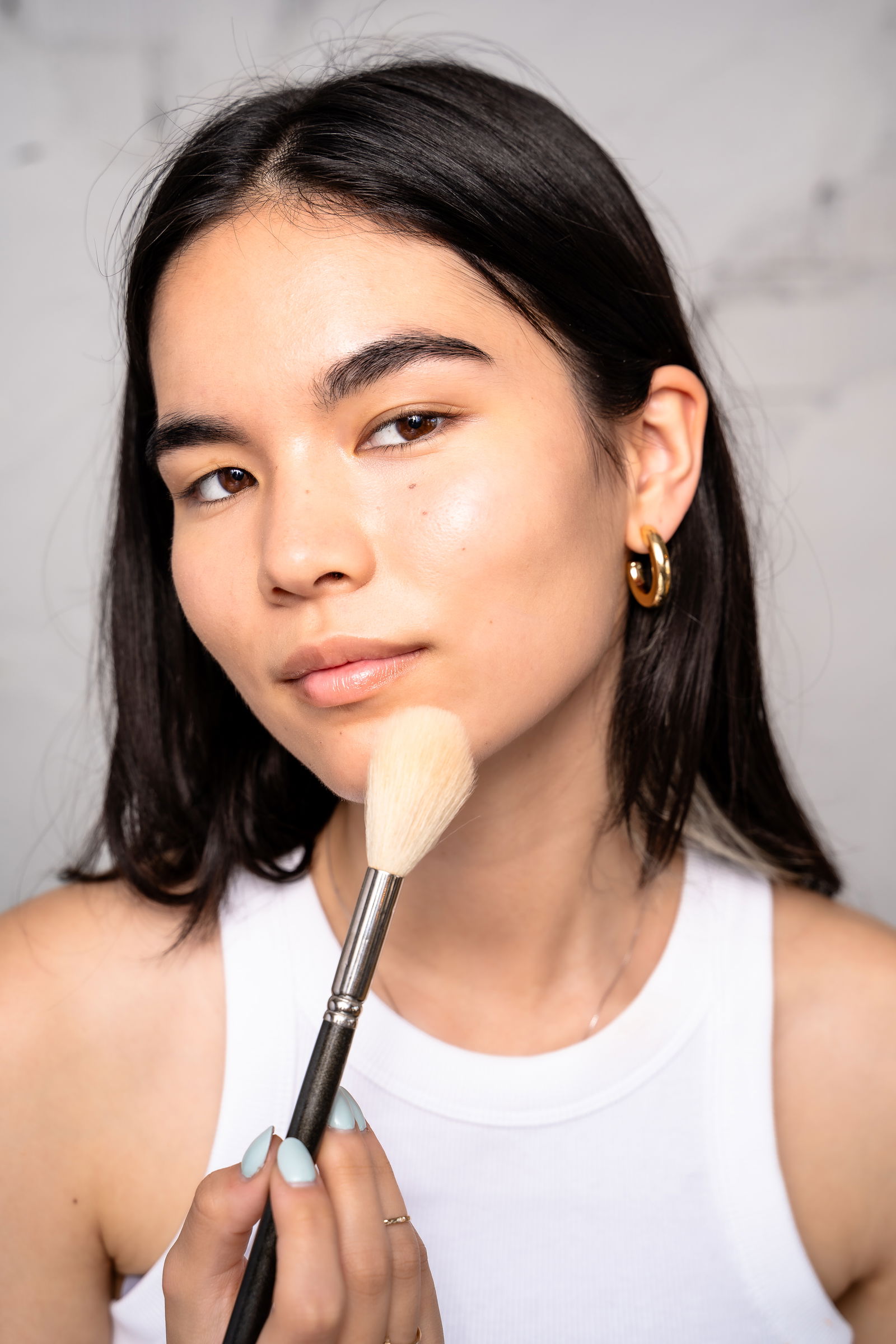 Girl showing how to apply makeup powder to chin