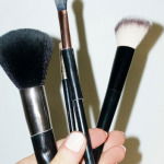 Hand holding make-up beauty cosmetics brushes and hard direct flashlight