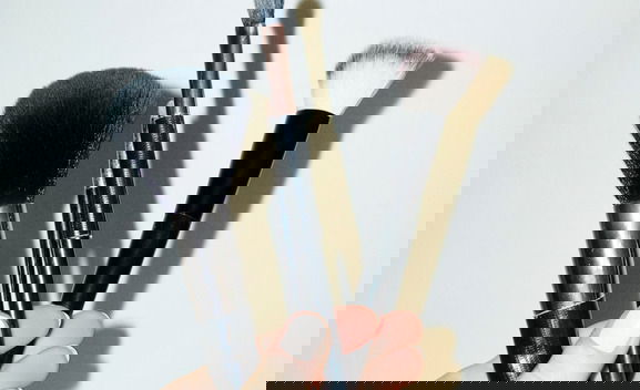 Hand holding make-up beauty cosmetics brushes and hard direct flashlight